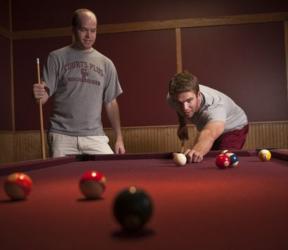 two students playing pool in a game room