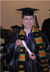 smiling graduate in cap and gown holding diploma