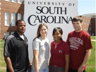 four students in front of university of south carolina sign