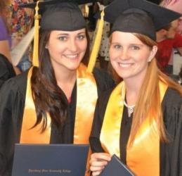 two female graduates holding diplomas