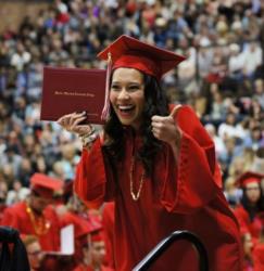 graduate jubilantly holding diploma at ceremony